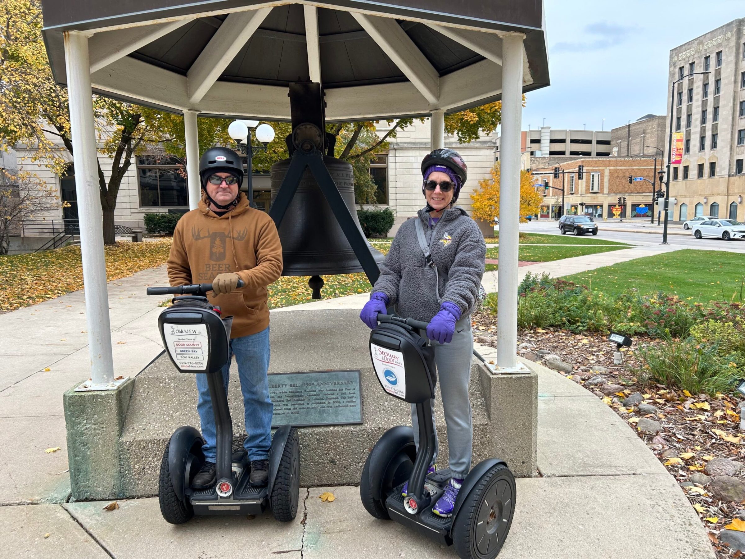 Couple in front of bell on Segways